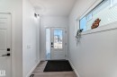 Entryway featuring a white paneled door with black hardware, wood-finish flooring, and a sidelight window - 3247 Chernowski Way, Edmonton, AB  - Indoor Photo Showing Other Room 