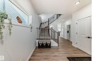 Expansive entryway featuring wood-finish flooring, a two-story staircase with dark balusters, and recessed ceiling lighting - 3247 Chernowski Way, Edmonton, AB  - Indoor Photo Showing Other Room 