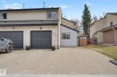 Stucco exterior with a dual garage featuring panel-style doors and exterior lighting fixtures - 17305 60 Ave, Edmonton, AB 