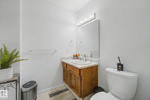 Bathroom featuring a vanity with a laminate countertop, integrated sink, and wood-finish cabinetry - 17305 60 Ave, Edmonton, AB 