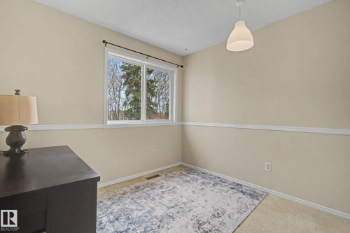 Room featuring a large window, neutral wall paint, white trim, and a ceiling-mounted light fixture - 17305 60 Ave, Edmonton, AB 