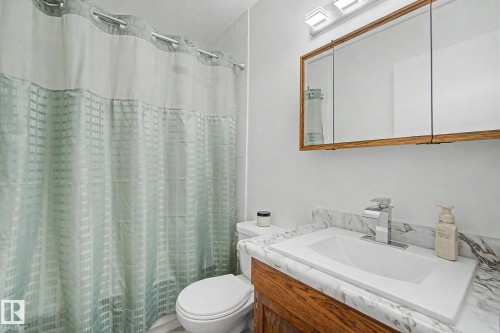 Bathroom featuring a white ceramic toilet and a vanity with a wood-finish cabinet - 17305 60 Ave, Edmonton, AB 