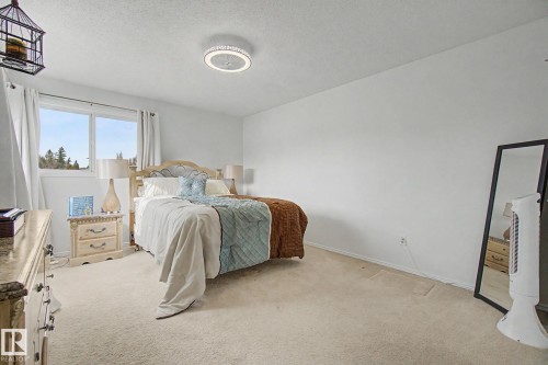 Bright interior featuring a window with outdoor scenery, recessed lighting, and light-toned carpeting - 17305 60 Ave, Edmonton, AB 