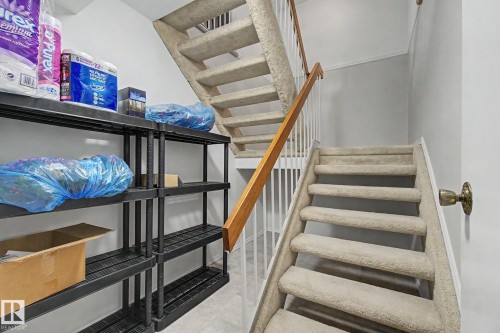 Carpeted staircase with a wood handrail and white balusters - 17305 60 Ave, Edmonton, AB 