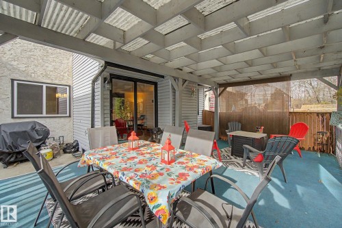 Covered patio featuring a slatted roof structure, blue painted concrete floor, and direct access to the interior via sliding glass doors - 17305 60 Ave, Edmonton, AB 