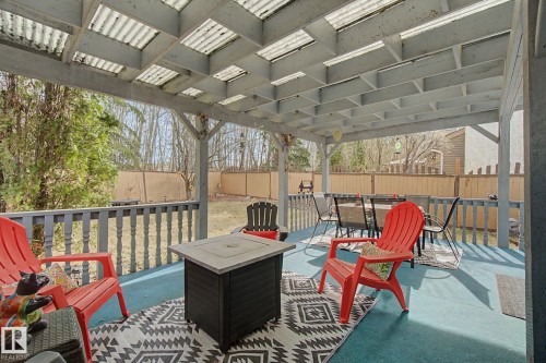 Covered deck featuring a corrugated roof, painted railings, and an expansive backyard - 17305 60 Ave, Edmonton, AB 