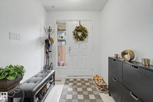 Entryway featuring a white door with a clear glass sidelight, light-colored flooring, and a flush-mount ceiling light - 17305 60 Ave, Edmonton, AB 