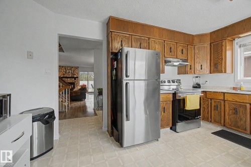 Kitchen featuring wood-finish cabinetry, stainless steel appliances, and light-toned flooring - 17305 60 Ave, Edmonton, AB 