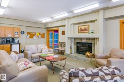 The property features a spacious room with a stone-tiled fireplace, a kitchenette with wood cabinetry, and a sliding glass door - 