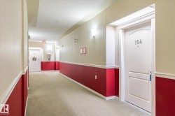 Well-lit hallway with neutral tone carpet and walls featuring a bold red lower section with white trim - 