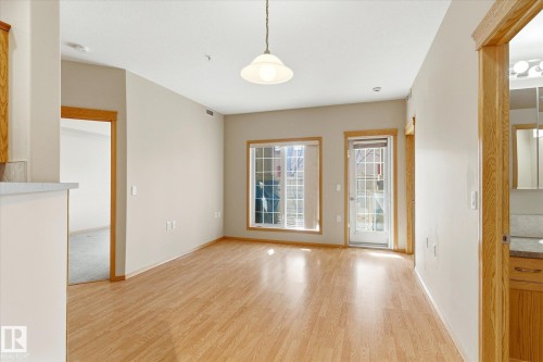 Living area featuring hardwood flooring, light-colored walls, and a window with a view to the outdoors - 104 612 111 Street Sw, Edmonton, AB - Indoor Photo Showing Other Room