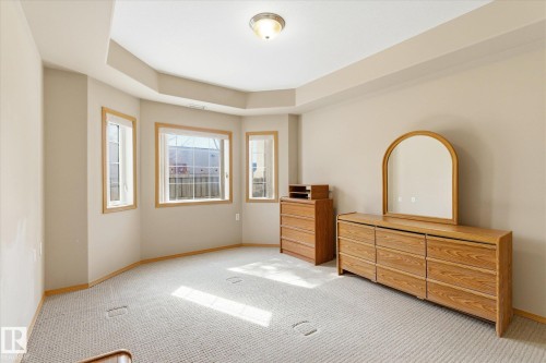 This bright room features a tray ceiling, light-colored walls, and a carpeted floor - 104 612 111 Street Sw, Edmonton, AB - Indoor