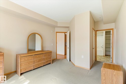 The property features neutral-toned walls, a light-colored carpet, and wood trim around the doors - 104 612 111 Street Sw, Edmonton, AB - Indoor