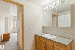 Bathroom vanity featuring a single sink, wood cabinetry, and a mirrored medicine cabinet with overhead lighting - 