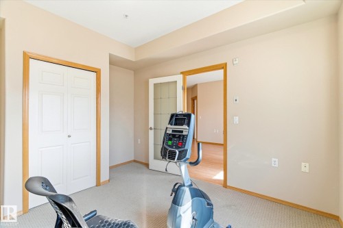 Versatile room featuring light-colored walls, neutral carpeting, and a white bi-fold closet with wood trim - 104 612 111 Street Sw, Edmonton, AB - Indoor Photo Showing Other Room