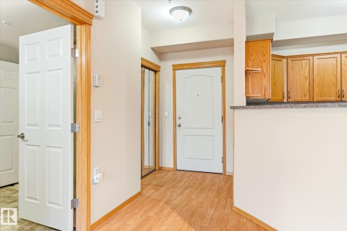 Entryway with hardwood flooring, a white paneled door, and wood trim throughout - 104 612 111 Street Sw, Edmonton, AB - Indoor Photo Showing Other Room