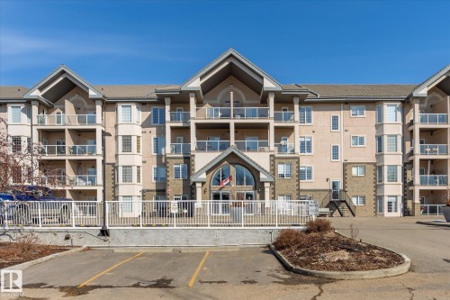 The property features a multi-story building with balconies, a pitched roof, and a combination of stucco and stone exterior finishes - 104 612 111 Street Sw, Edmonton, AB - Outdoor With Facade