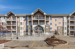 The property features a multi-story building with balconies, a pitched roof, and a combination of stucco and stone exterior finishes - 