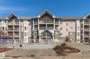 The property features a multi-story building with balconies, a pitched roof, and a combination of stucco and stone exterior finishes - 104 612 111 Street Sw, Edmonton, AB  - Outdoor With Facade 