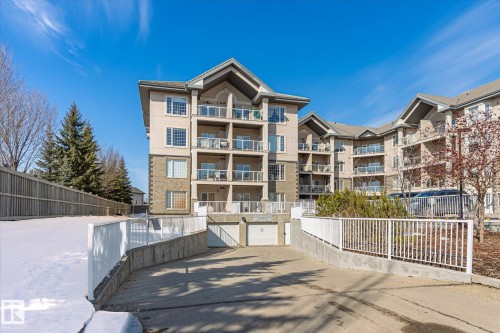 The property features a multi-story building with a stone and stucco facade, private balconies, and an underground parking entrance - 104 612 111 Street Sw, Edmonton, AB - Outdoor With Facade