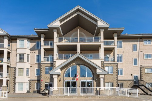 The property features a multi-story facade with balconies, prominent gabled rooflines, and a welcoming main entrance with an arched window - 104 612 111 Street Sw, Edmonton, AB - Outdoor With Facade