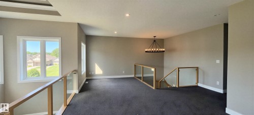 Open loft area featuring neutral wall tones, dark carpeting, and recessed lighting - 53 Mockingbird Cres, Fort Saskatchewan, AB - Indoor Photo Showing Other Room