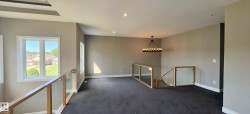 Open loft area featuring neutral wall tones, dark carpeting, and recessed lighting - 
