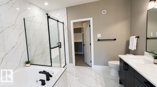 Bathroom featuring a frameless glass shower enclosure with black hardware, a soaking tub with black fixtures, and large-format porcelain tile flooring - 53 Mockingbird Cres, Fort Saskatchewan, AB - Indoor Photo Showing Bathroom