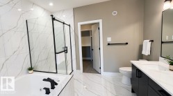 Bathroom featuring a frameless glass shower enclosure with black hardware, a soaking tub with black fixtures, and large-format porcelain tile flooring - 