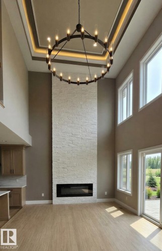 Two-story living area with a floor-to-ceiling textured stone fireplace and a linear electric insert - 53 Mockingbird Cres, Fort Saskatchewan, AB - Indoor Photo Showing Other Room With Fireplace