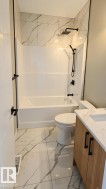 Full bathroom featuring a tub/shower combination with matte black fixtures and a rain shower head - 
