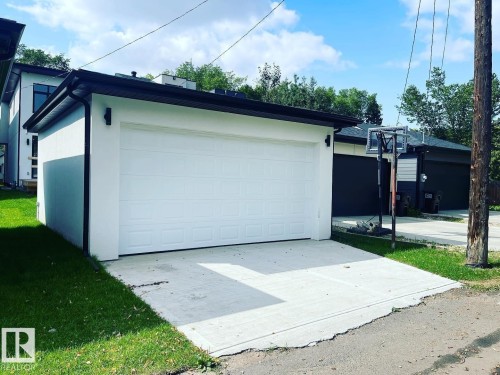 Detached garage featuring a white paneled door, black trim, and a concrete driveway apron - 10227 146 Street, Edmonton, AB - Outdoor