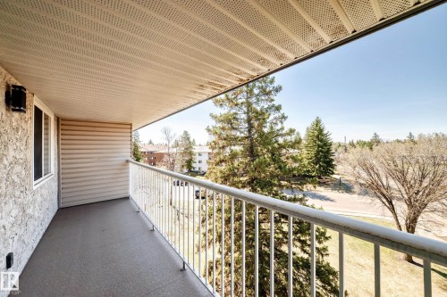 Covered outdoor balcony with a light-colored stucco exterior wall and horizontal siding - 423 5125 Riverbend Road, Edmonton, AB - Outdoor With Balcony With Exterior