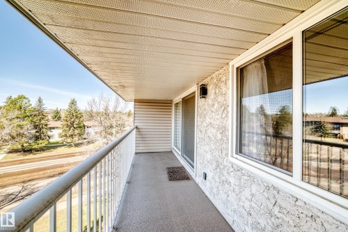 Balcony with textured exterior wall, white window frames, and a sliding glass door - 423 5125 Riverbend Road, Edmonton, AB - Outdoor With Balcony With Exterior