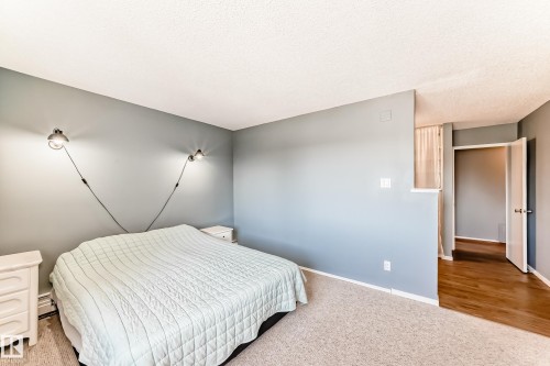 Bedroom with neutral wall tones, textured ceiling, and soft carpet flooring - 423 5125 Riverbend Road, Edmonton, AB - Indoor Photo Showing Bedroom