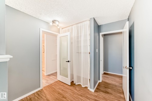 Interior hallway featuring wood-finish flooring and track lighting - 423 5125 Riverbend Road, Edmonton, AB - Indoor Photo Showing Other Room