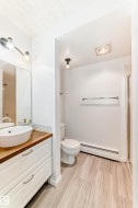 Bathroom featuring a white vanity with wood-finish countertop and vessel sink - 