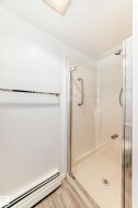 Shower enclosure featuring clear glass panels and a chrome handle, complemented by wood-finish flooring and a chrome towel bar - 