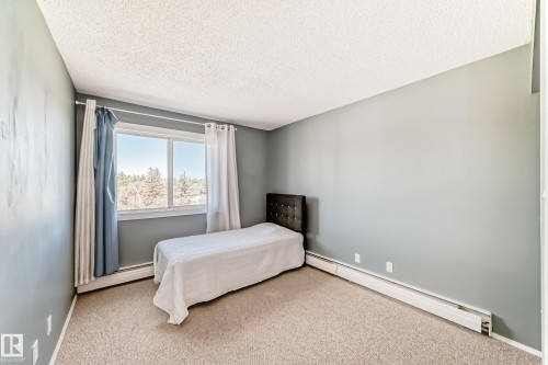 Carpeted room with a large window and baseboard heating - 423 5125 Riverbend Road, Edmonton, AB - Indoor Photo Showing Bedroom