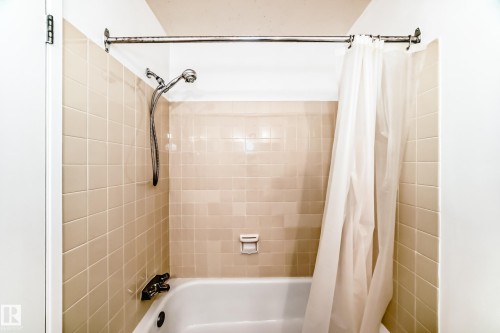 Bathtub with beige square wall tiles and a chrome shower fixture - 423 5125 Riverbend Road, Edmonton, AB - Indoor Photo Showing Bathroom