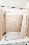 White porcelain bathtub with chrome fixtures and a handheld showerhead - 