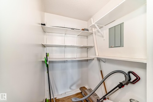 Utility closet featuring white walls, wood-finish flooring, a white textured ceiling, and multiple white wall-mounted storage shelves - 423 5125 Riverbend Road, Edmonton, AB - Indoor With Storage