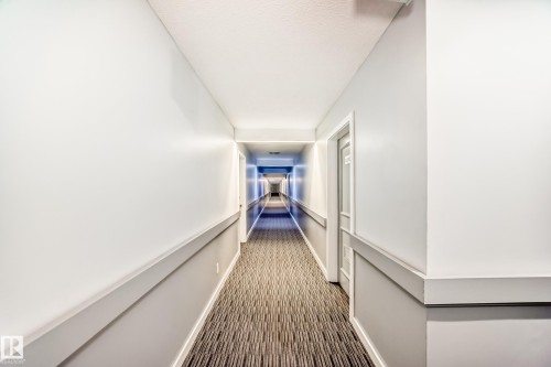 Hallway featuring light gray walls, white trim, and patterned carpeting - 423 5125 Riverbend Road, Edmonton, AB - Indoor Photo Showing Other Room