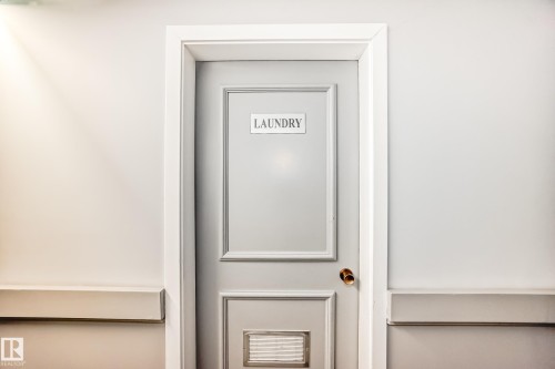 Laundry room entrance with a paneled door, brass hardware, and white trim - 423 5125 Riverbend Road, Edmonton, AB - Indoor Photo Showing Other Room