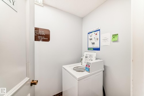 Dedicated laundry area featuring a top-loading washer, light gray wall paint, and a dark tile base - 423 5125 Riverbend Road, Edmonton, AB - Indoor Photo Showing Laundry Room