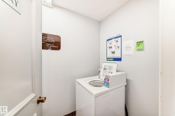 Dedicated laundry area featuring a top-loading washer, light gray wall paint, and a dark tile base - 