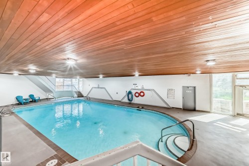 Indoor swimming pool with wood-finish ceiling, integrated overhead lighting, and large windows - 423 5125 Riverbend Road, Edmonton, AB - Indoor Photo Showing Other Room With In Ground Pool