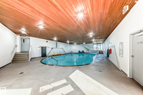 Indoor swimming pool featuring a curved design, surrounded by a light-colored non-slip floor - 423 5125 Riverbend Road, Edmonton, AB - Indoor Photo Showing Other Room With In Ground Pool