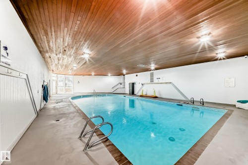 Indoor swimming pool featuring a curved design and integrated ladder access - 423 5125 Riverbend Road, Edmonton, AB - Indoor Photo Showing Other Room With In Ground Pool