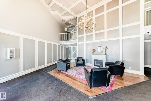 Two-story ceiling with coffered detail, featuring a chandelier and a fireplace with a white mantel - 423 5125 Riverbend Road, Edmonton, AB - Indoor With Fireplace